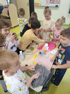 Dzieci z oddziału przedszkolnego poznają za pomocą dotyku przedmioty o różnych kształtach i fakturach.