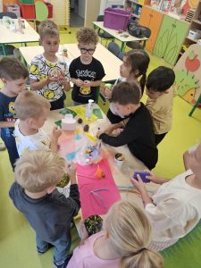 Dzieci oglądają i dotykają różnorodnych przedmiotów podczas zajęć poświęconych poznawaniu świata za pomocą zmysłów.