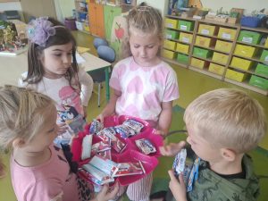 Dzieci częstują się słodkimi upominkami podczas obchodów Dnia Chłopaka w oddziale przedszkolnym.