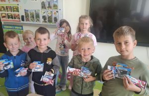 Grupa dzieci z oddziału przedszkolnego pozuje w sali z upominkami przygotowanymi z okazji Dnia Chłopaka.