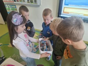 Dzieci z oddziału przedszkolnego wybierają samochodziki z koszyka z upominkami z okazji Dnia Chłopaka.