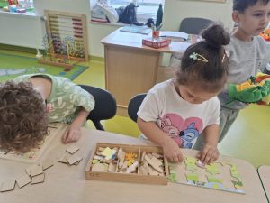 Dziewczynka układa drewniane puzzle ze zwierzętami, a obok chłopiec rozwiązuje zadanie z wykorzystaniem układanki edukacyjnej.
