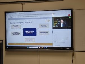 Na monitorze interaktywnym wyświetlana jest prezentacja „Czym jest inteligencja finansowa?”, przedstawiająca zagadnienia oszczędzania, zarządzania budżetem, świadomej konsumpcji i odpowiedzialnego pożyczania.