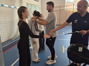 Moment wręczania medali najlepszym uczestniczkom wioślarskiej rywalizacji przez trenerów prowadzących spotkanie.