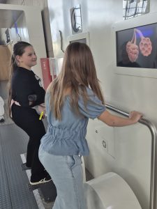 Dwie uczennice korzystają z interaktywnego stanowiska przedstawiającego budowę narządów ludzkiego ciała na ekranie.